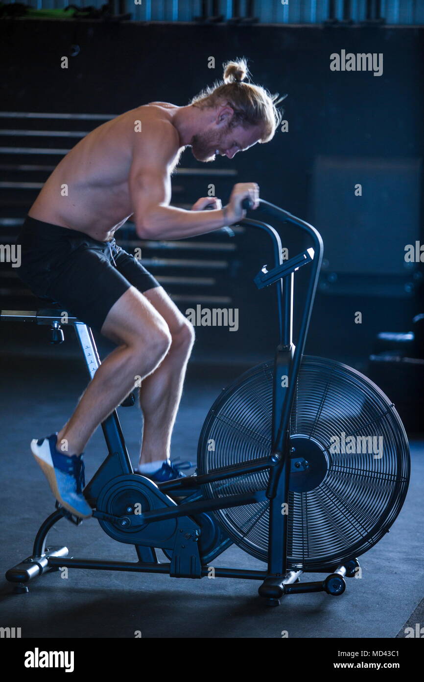 Hombre haciendo ejercicio en el gimnasio, con la resistencia del aire bicicleta Foto de stock