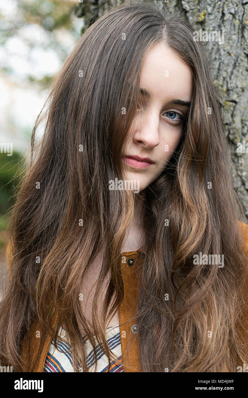 Una chica adolescente (13 años) con pelo largo, mirando a la cámara. Foto de stock