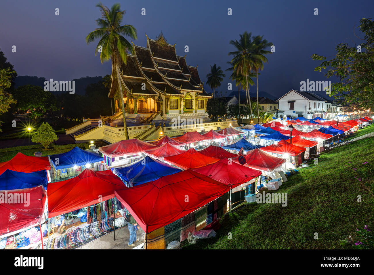 Mercado Nocturno y lit Haw Pha Bang templo, también conocido como Palacio Real o capilla, junto al Palacio Real en Luang Prabang, Laos, al anochecer. Foto de stock