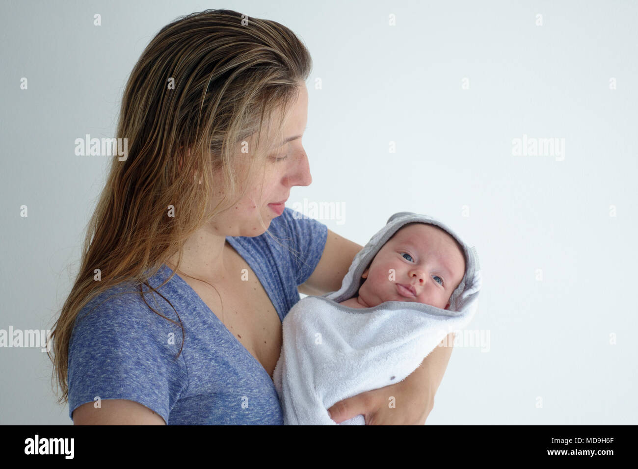 Madre sosteniendo a su pequeño y lindo bebé envuelto en una toalla Foto de stock