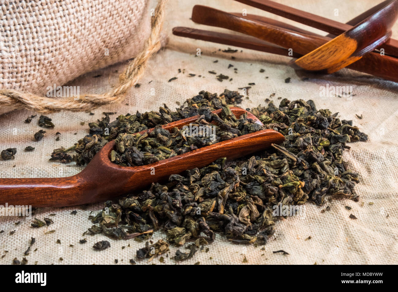 Oolong té chino. Montón de hojas de té en el mantel de lino con textura con cuchara de bambú. Aromática y saludable bebida ampliamente utilizado en el mundo. Foto de stock