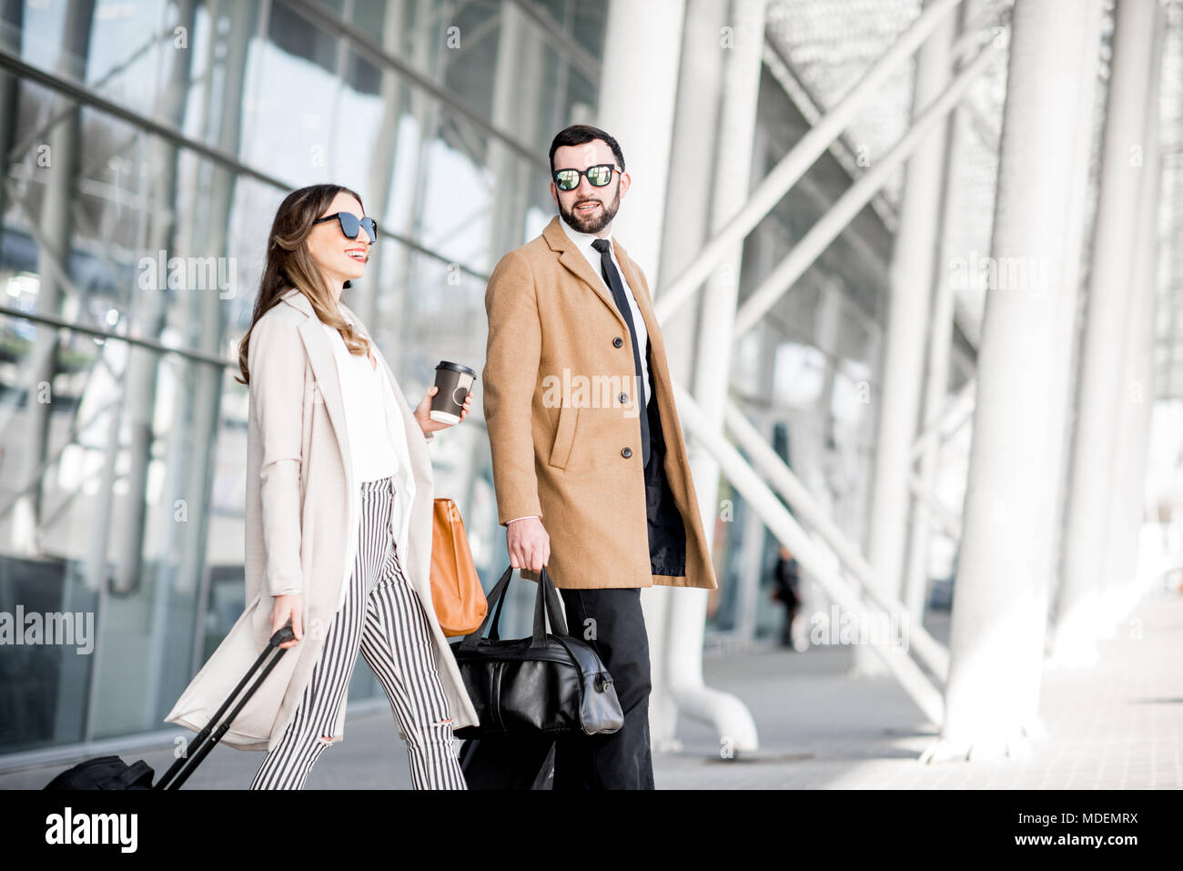 Pareja de negocios en abrigos caminar aeropuerto con el equipaje durante el viaje de negocios Fotografía stock -