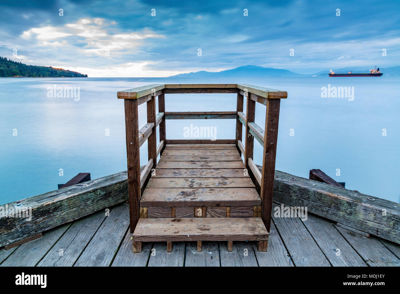 Una plataforma de visualización de madera al final de un muelle se asoma a un buque en el mar tranquilo; en Vancouver, British Columbia, Canadá Foto de stock