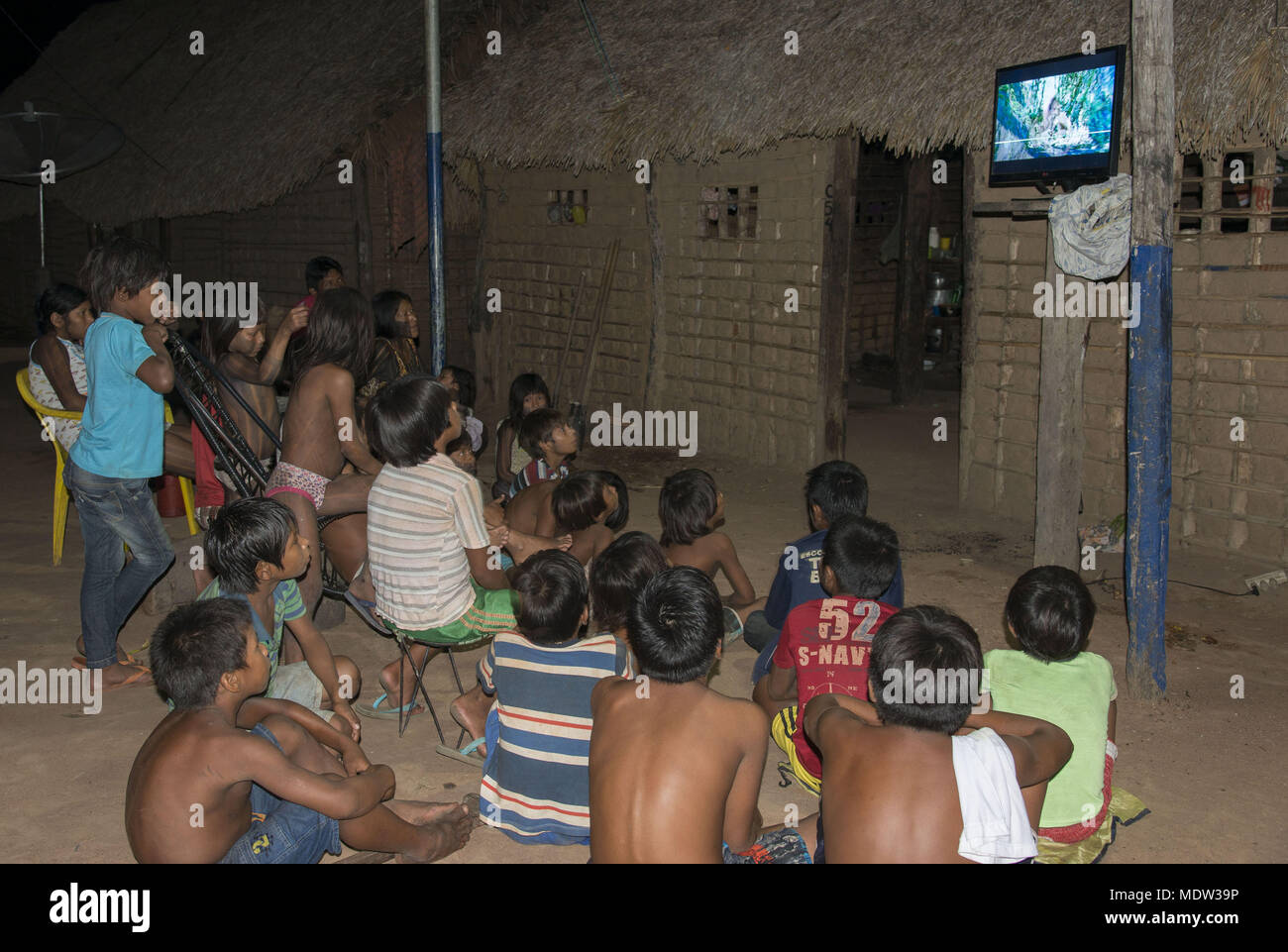 Los niños Kayapó Moikarako poblado viendo televisión en el patio - Tierras Indígenas Kayapó Foto de stock