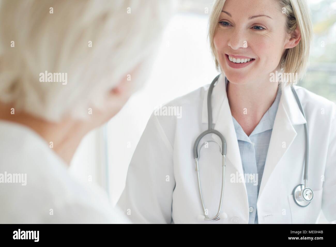 Doctora sonriendo hacia el paciente. Foto de stock