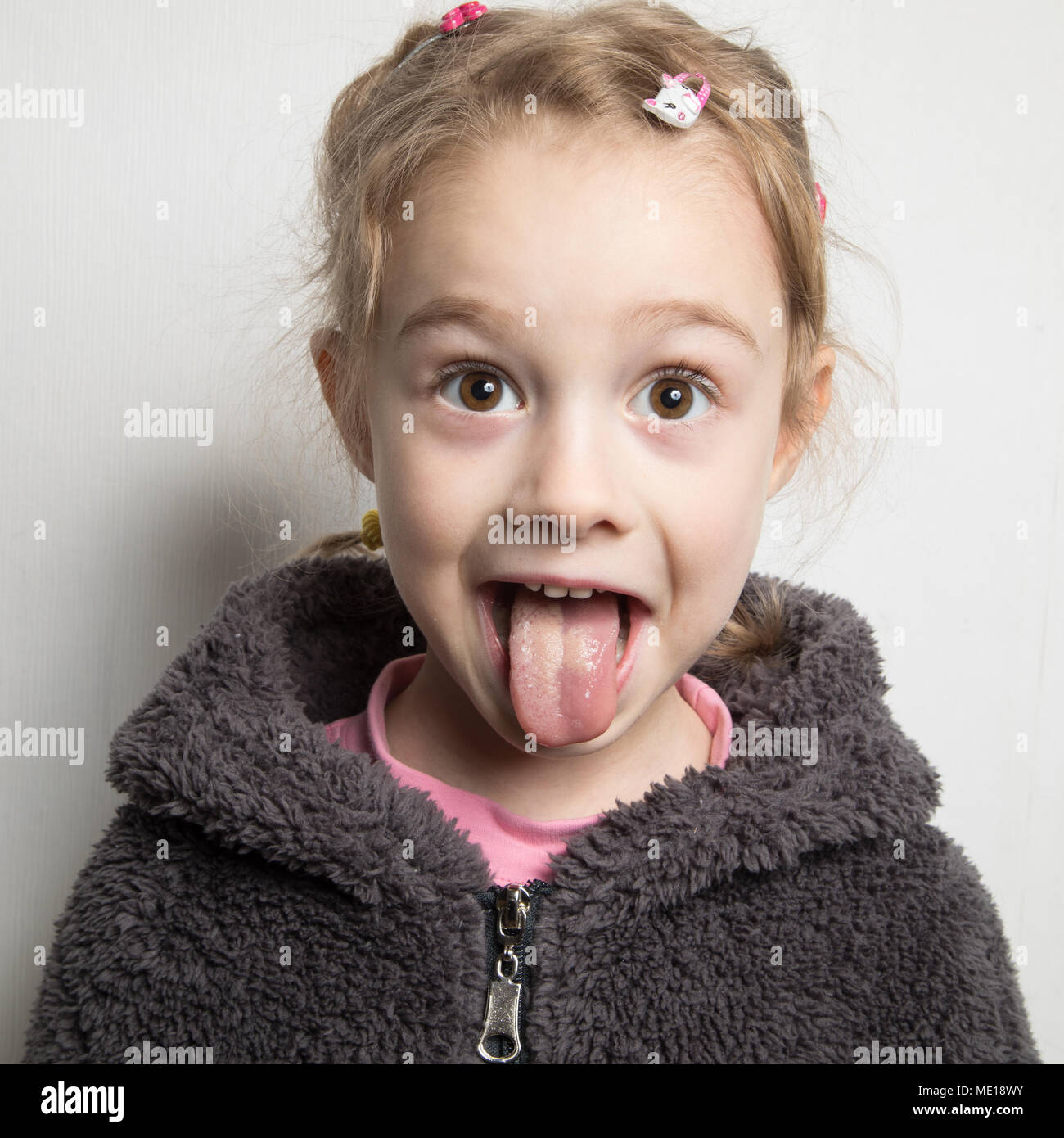 Niña feliz mostrando su lengua. Foto de stock