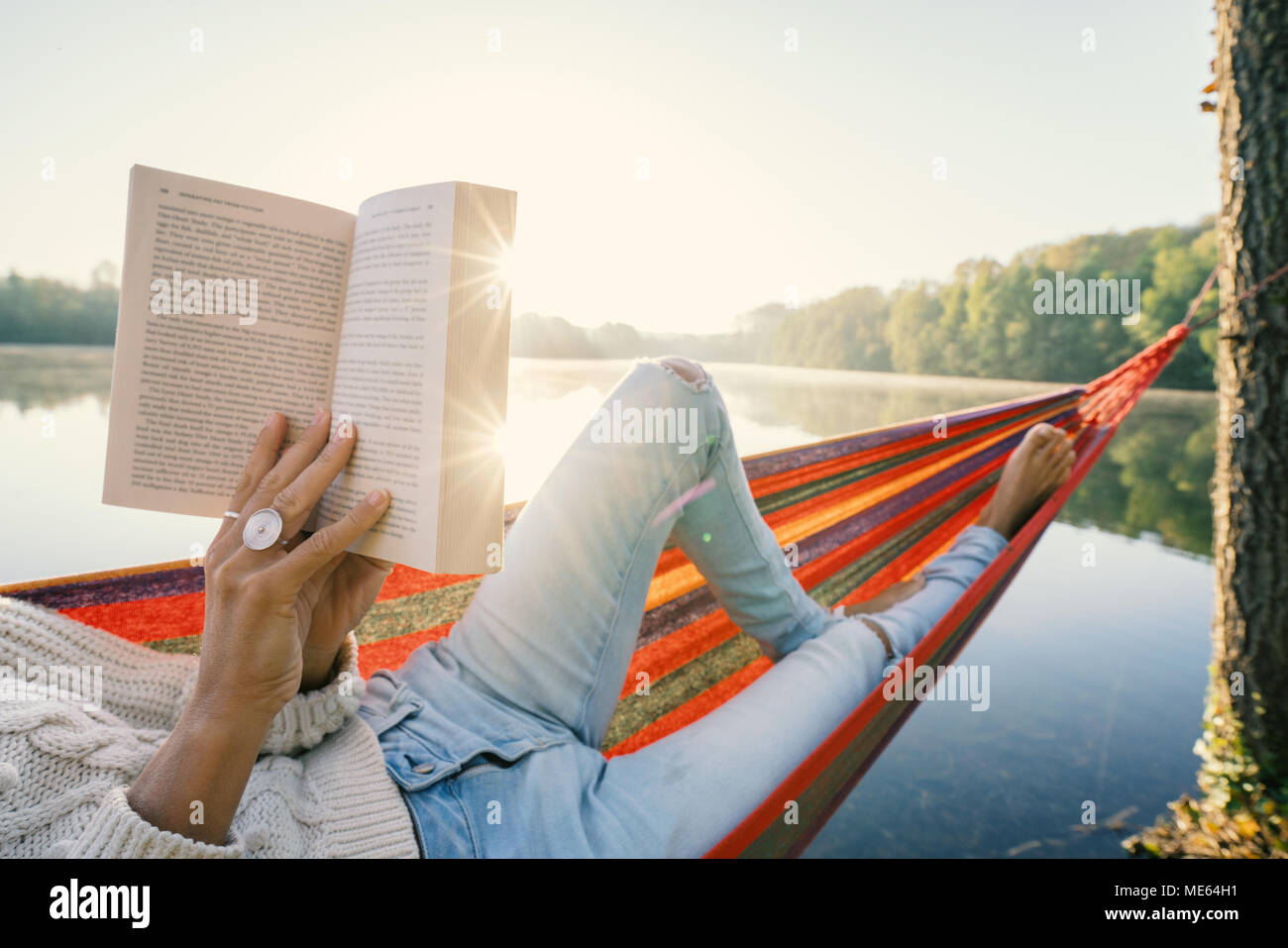 Punto de vista, mujer, relajarse en una hamaca en el lago al amanecer leyendo un libro. Las personas viajan relajación bienestar concepto de aprendizaje. Francia, Europa Foto de stock