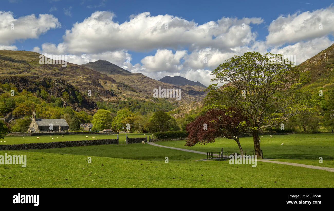 Una vista de la Iglesia de Santa María,Beddgelert,Gwynedd,el Parque Nacional de Snowdonia, con montañas en el fondo Foto de stock