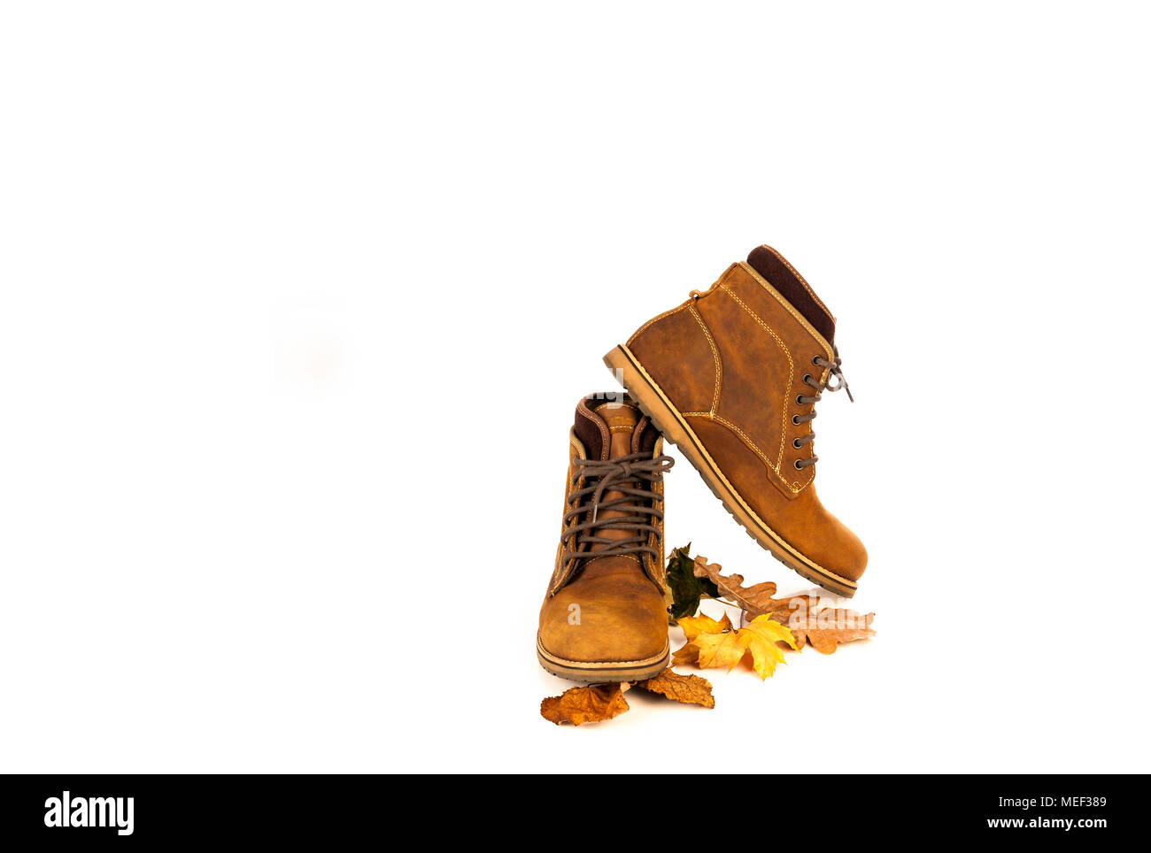 Cuero de Nubuck gamuza marrón mans botas con hojas de otoño Foto de stock