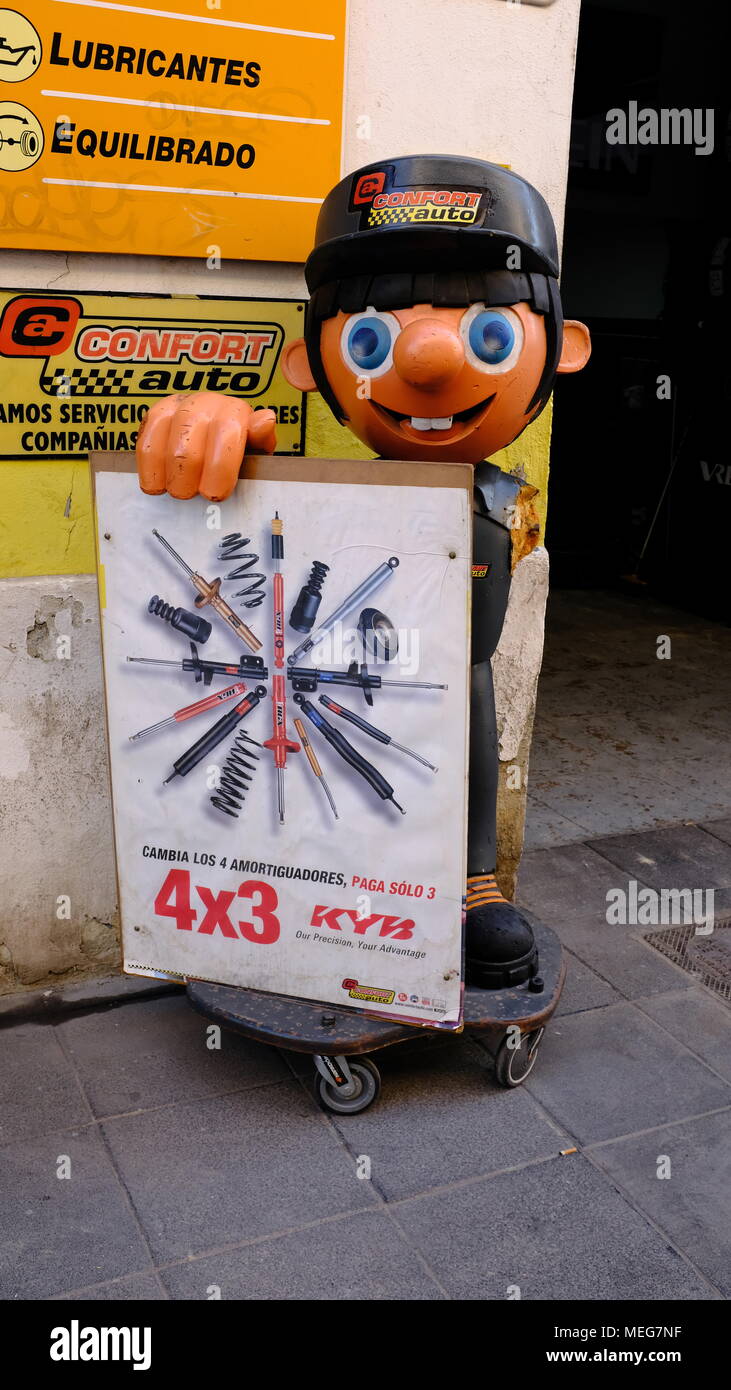 El siempre sonriente Confort Auto mascota mecánico sosteniendo un cartel fuera de un garaje en Valencia, España Foto de stock