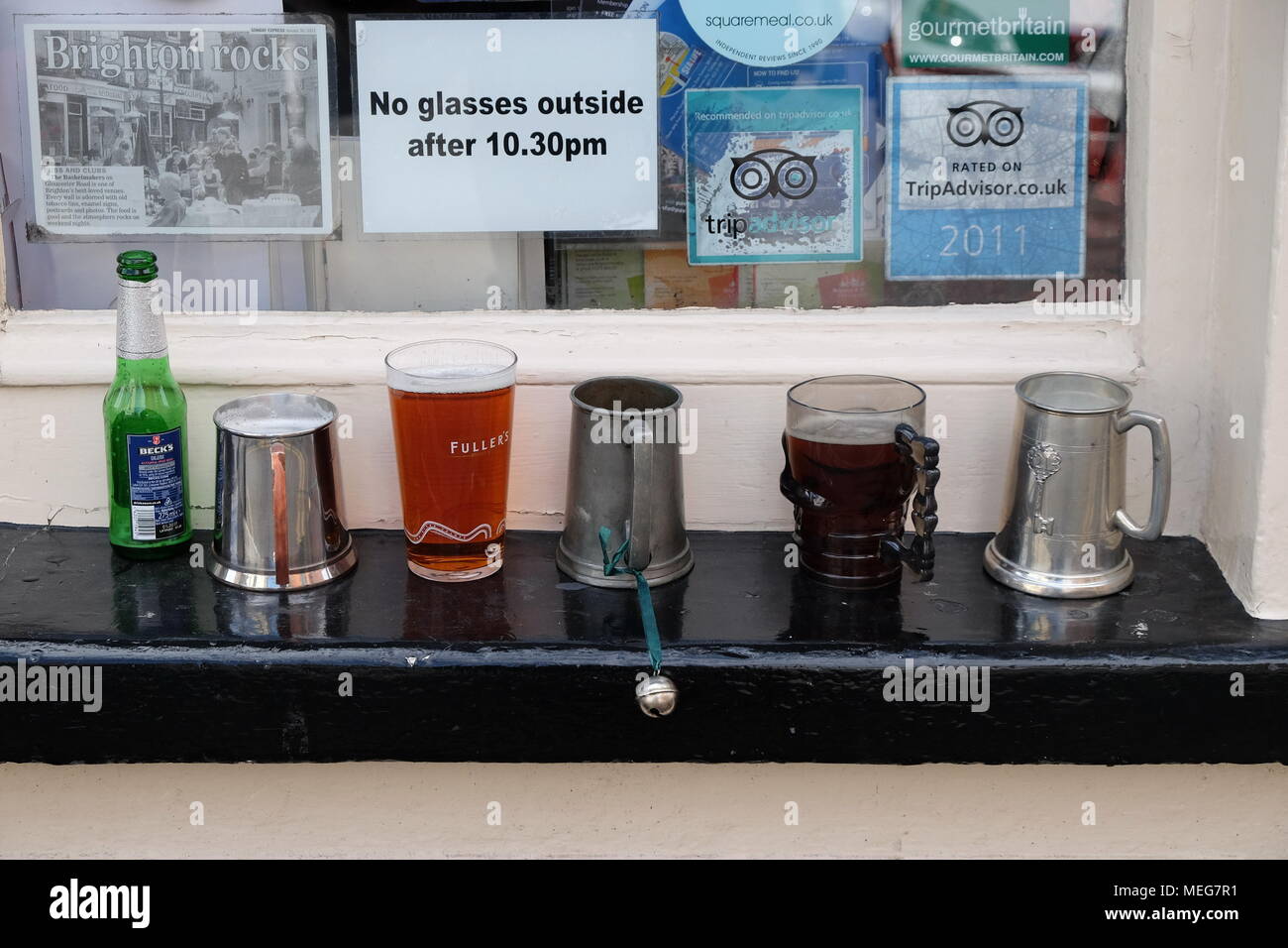 Assorted tankards y gafas en un pub la repisa de la ventana. Foto de stock