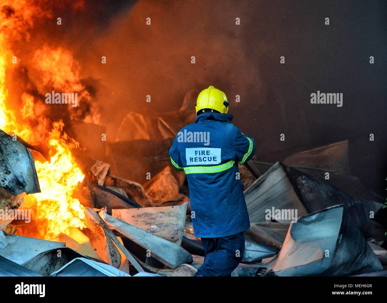El bombero luchando con el fuego, rescate en busca de supervivientes. Enormes llamas quemaron una empresa de reciclaje en Tirana, bombero de extinguir las llamas Foto de stock