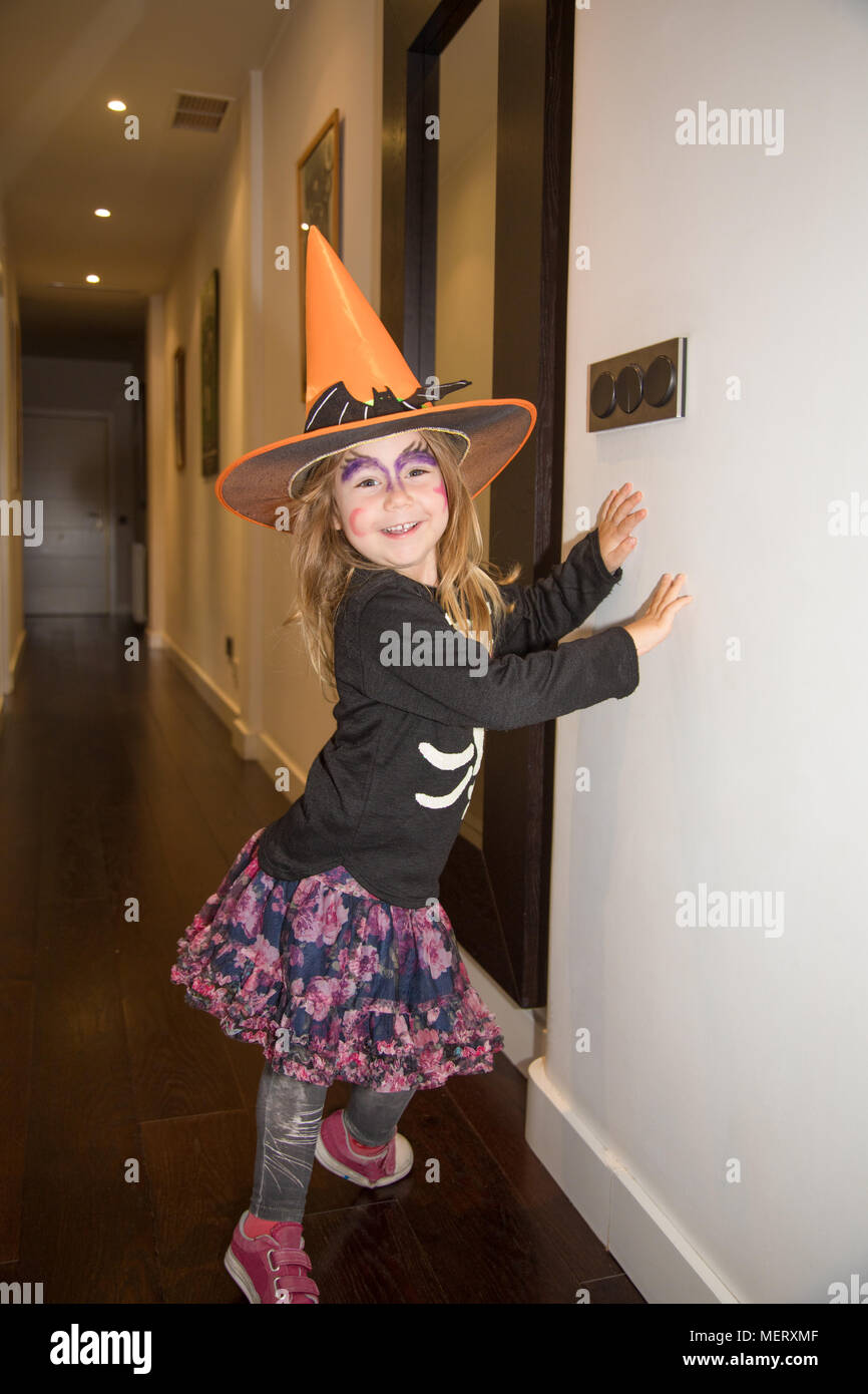 Retrato de cuatro años rubia niña disfraz para Halloween, con sombrero de  bruja naranja, suéter negro y el rostro pintado, mirando las caras  sonrientes Fotografía de stock - Alamy