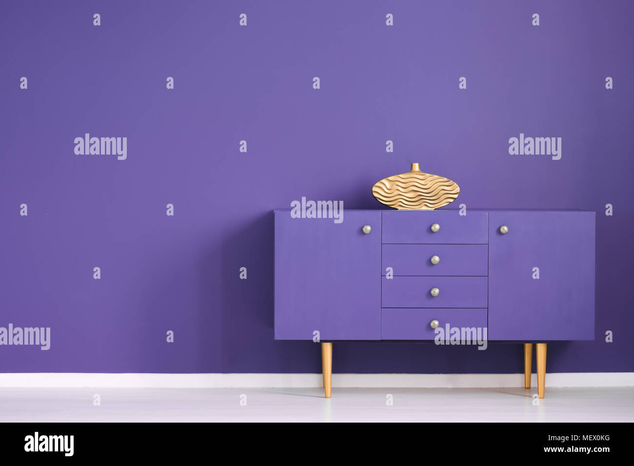 Jarrón de oro gabinete violeta contra la pared con copia en la antecámara del espacio interior Foto de stock