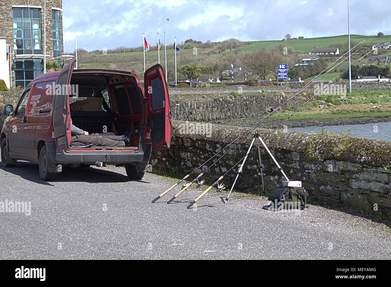 Pescador durmiendo en la parte de atrás de su camioneta mientras pescaba con 3 varillas en la Warren, rosscarbery Irlanda. Un popular destino turístico y de vacaciones. Foto de stock