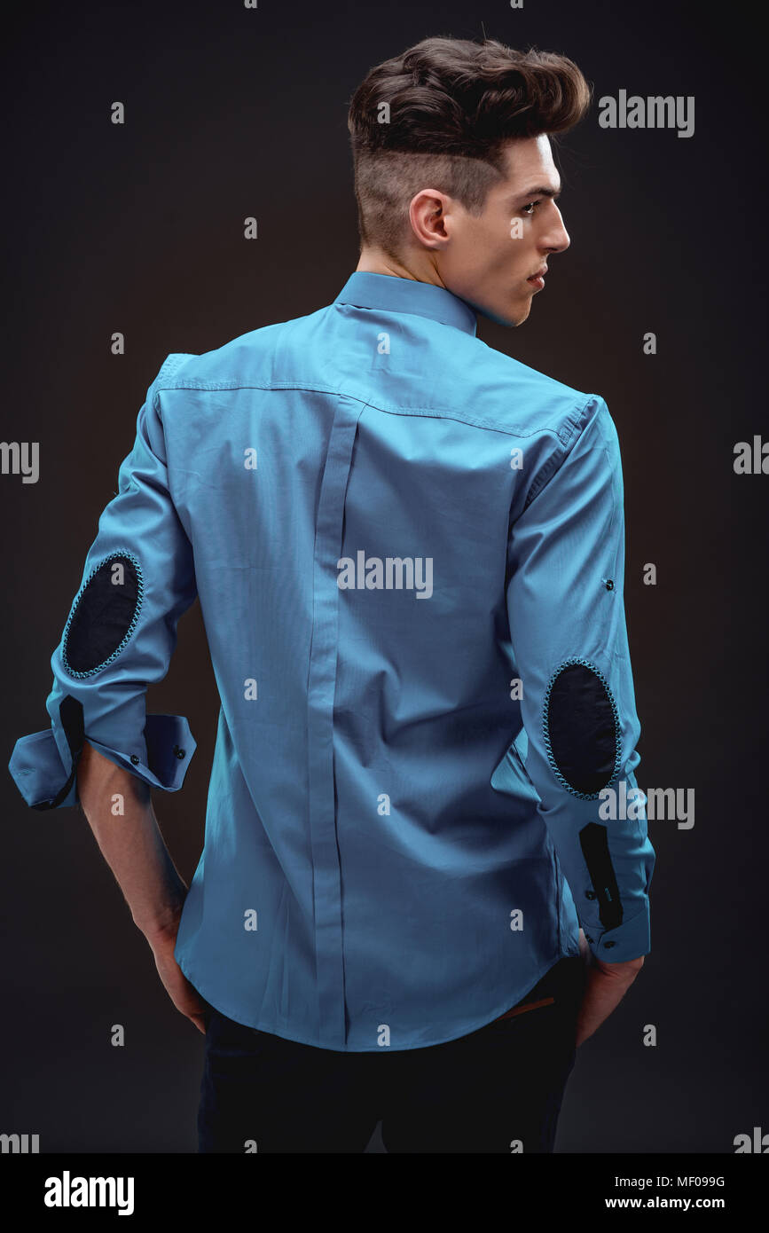 Vista trasera de un guapo de moda hombre en camisa de color turquesa. Fondo  negro Fotografía de stock - Alamy
