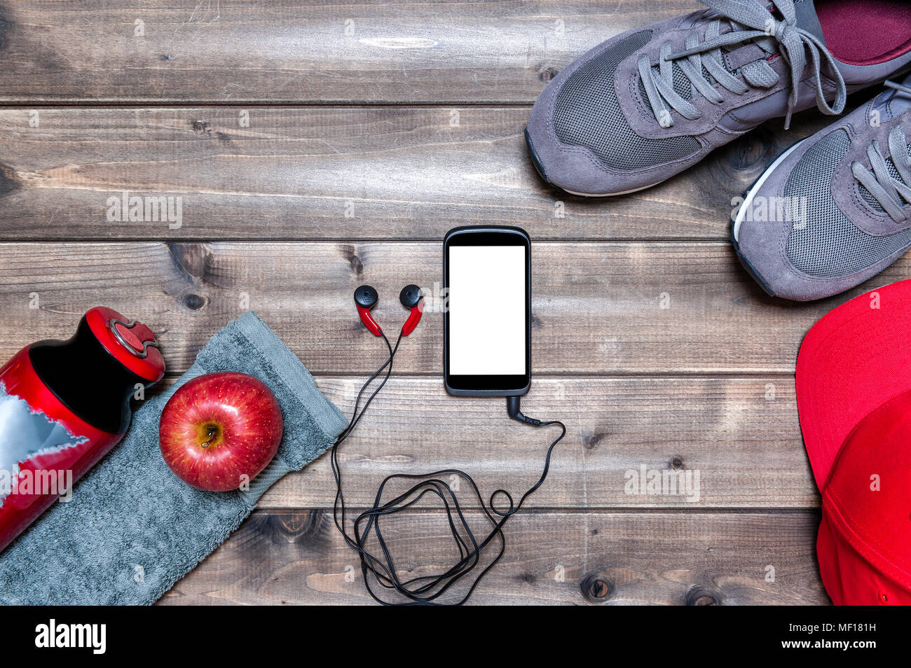 Vista superior de una manzana roja, zapatos deportivos, auriculares de audio,  smartphone, sombrero, toalla y botella de agua fotografiada sobre una mesa  de madera antigua. Espacio de texto Fotografía de stock -