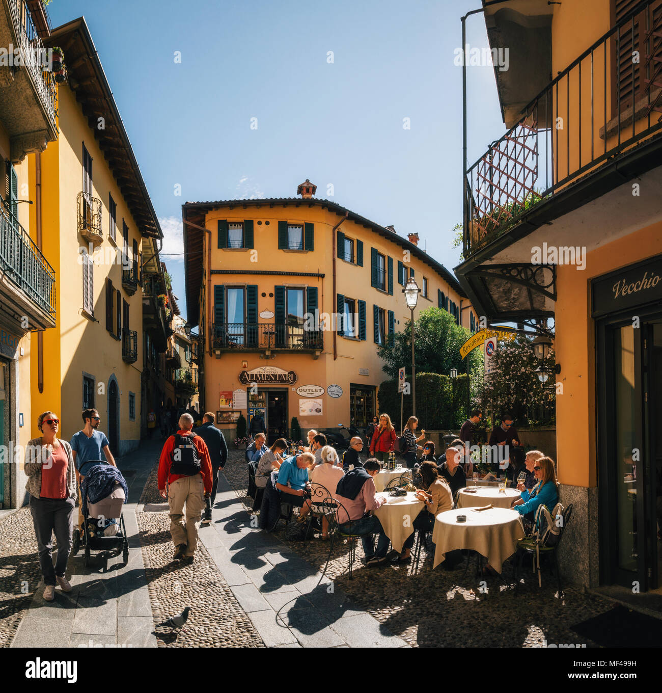 Bellagio, Italia - Octubre 7, 2017: Los turistas en la calle angosta con coloridas casas en la pequeña localidad de Bellagio, Italia durante el día soleado. Lago Foto de stock