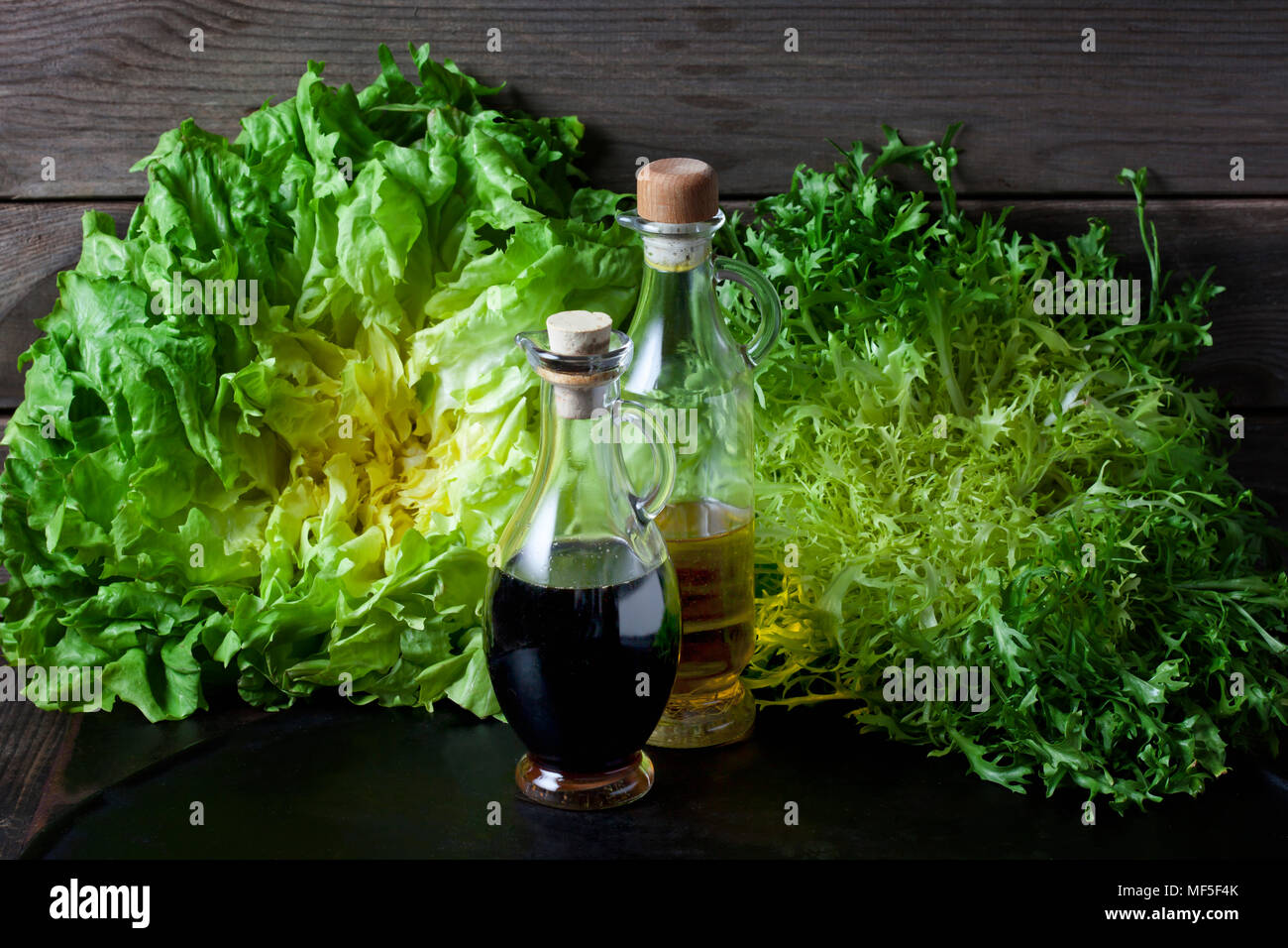 La escarola rizada y ensalada de endibias y vinagre y aceite de oliva en botellas Foto de stock