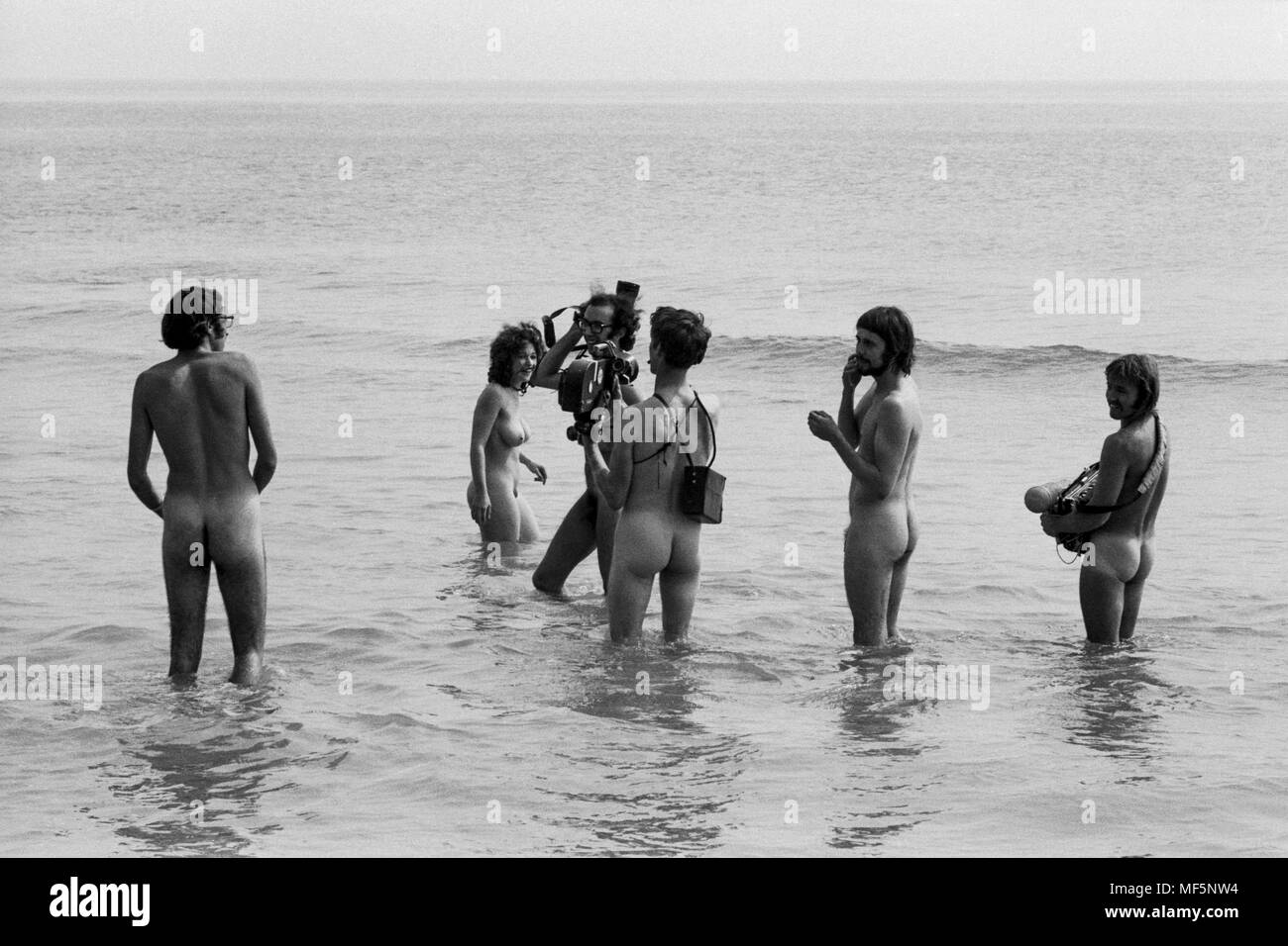 Un equipo de televisión en el 1970 en la Isla de Wight Festival pop, filmando los hippies flaco inmersión en agua dulce bahía para un informe de noticias. Guardias Hippy había ordenado a todos los miembros de la prensa que deseen acceder a la bahía a desnudarse a sí mismos antes de filmar o fotografiar, que los valientes miembros de los medios de comunicación hicieron alegremente. Foto de stock