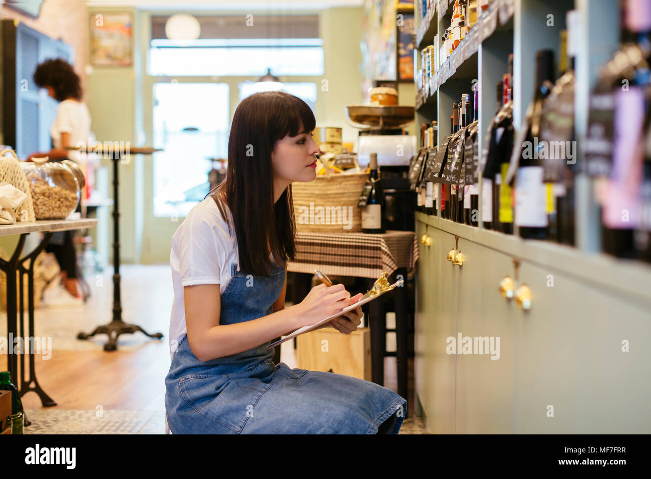 Mujer con el contenido del portapapeles en el estante en una tienda Foto de stock