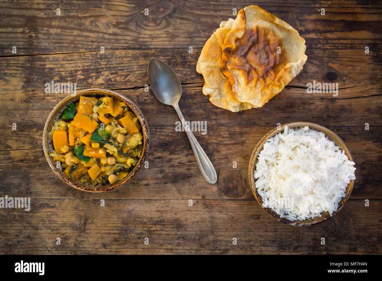 Plato de curry con coliflor, calabacita calabaza, espinaca y cilantro, papadam y arroz Foto de stock