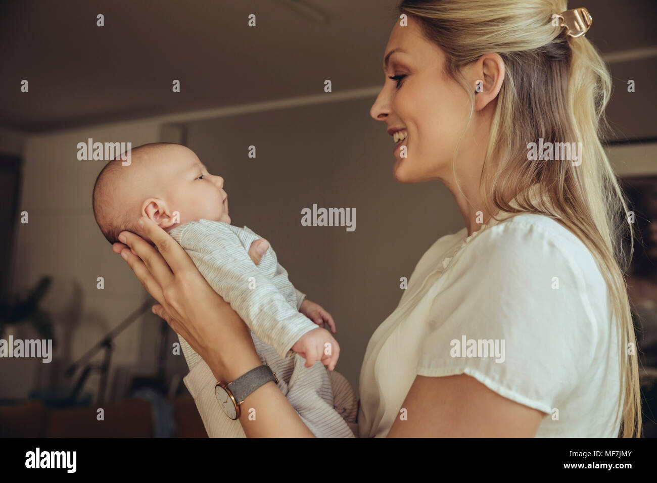 La madre sonríe al hablarle a su bebé recién nacido Foto de stock