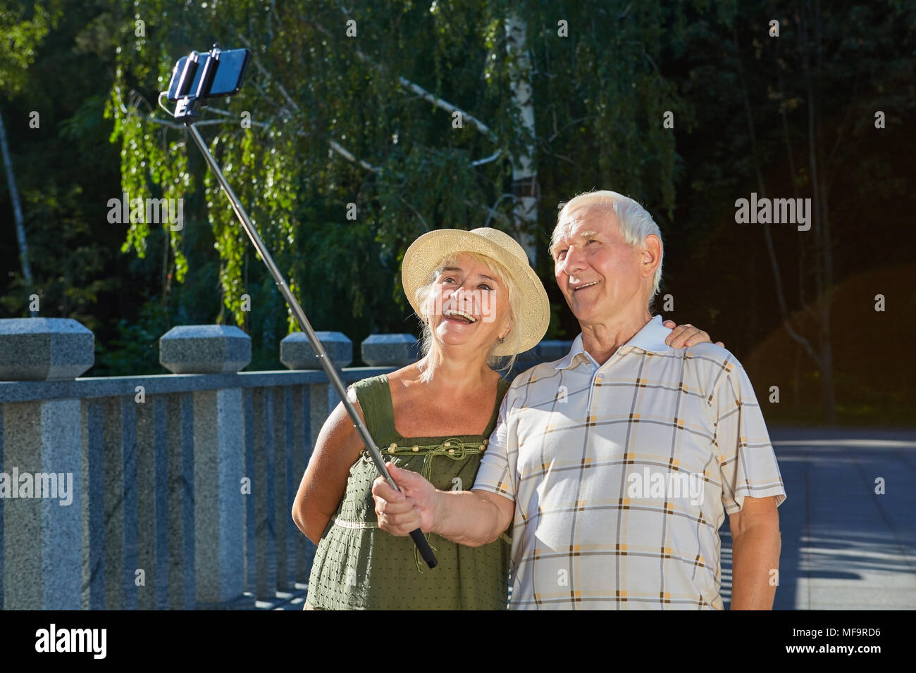 Las parejas ancianas teniendo selfie afuera. Viejo hombre feliz celebración monopie. Los hábitos de la buena fotografía. Foto de stock