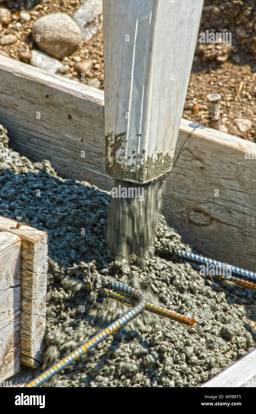 Se vierte la mezcla de hormigón húmedo en formas y sobre rebar para crear los cimientos de una casa. Foto de stock
