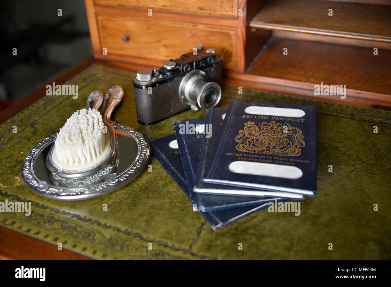 Antiguo mostrador de madera con pasaportes, vintage cámara Leica y cepillo  de plata sobre un espejo de plata, nombre ocultaron Fotografía de stock -  Alamy