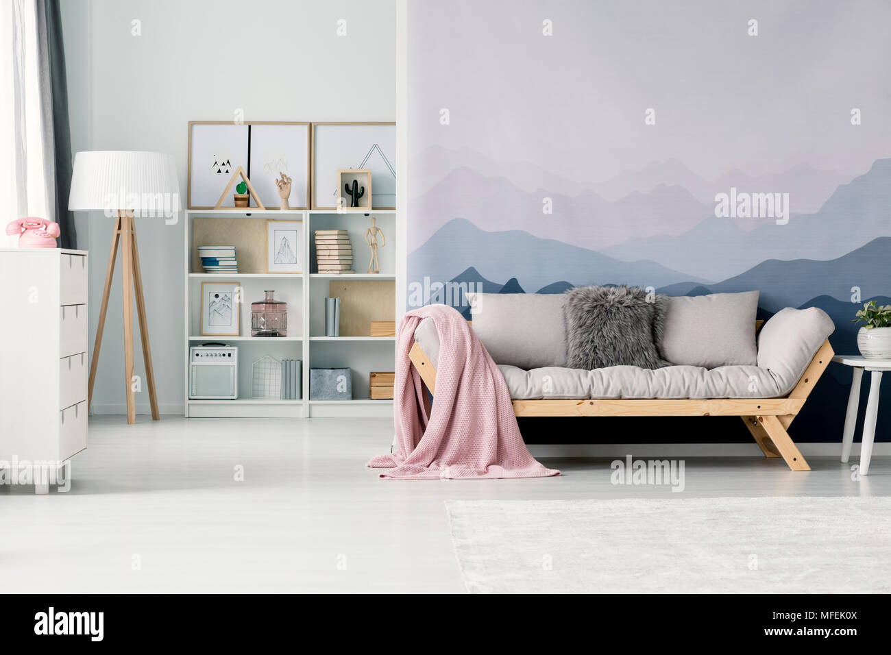 Acogedor salón interior con una manta de color rosa pastel sobre un sofá  color beige de pie contra una pared con papel tapiz de montaña Fotografía  de stock - Alamy