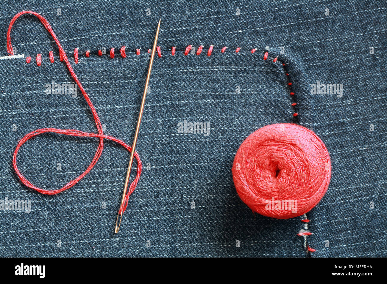 Primer plano de la aguja y el hilo rojo en el agujero agobiados por la  textura jeans Fotografía de stock - Alamy