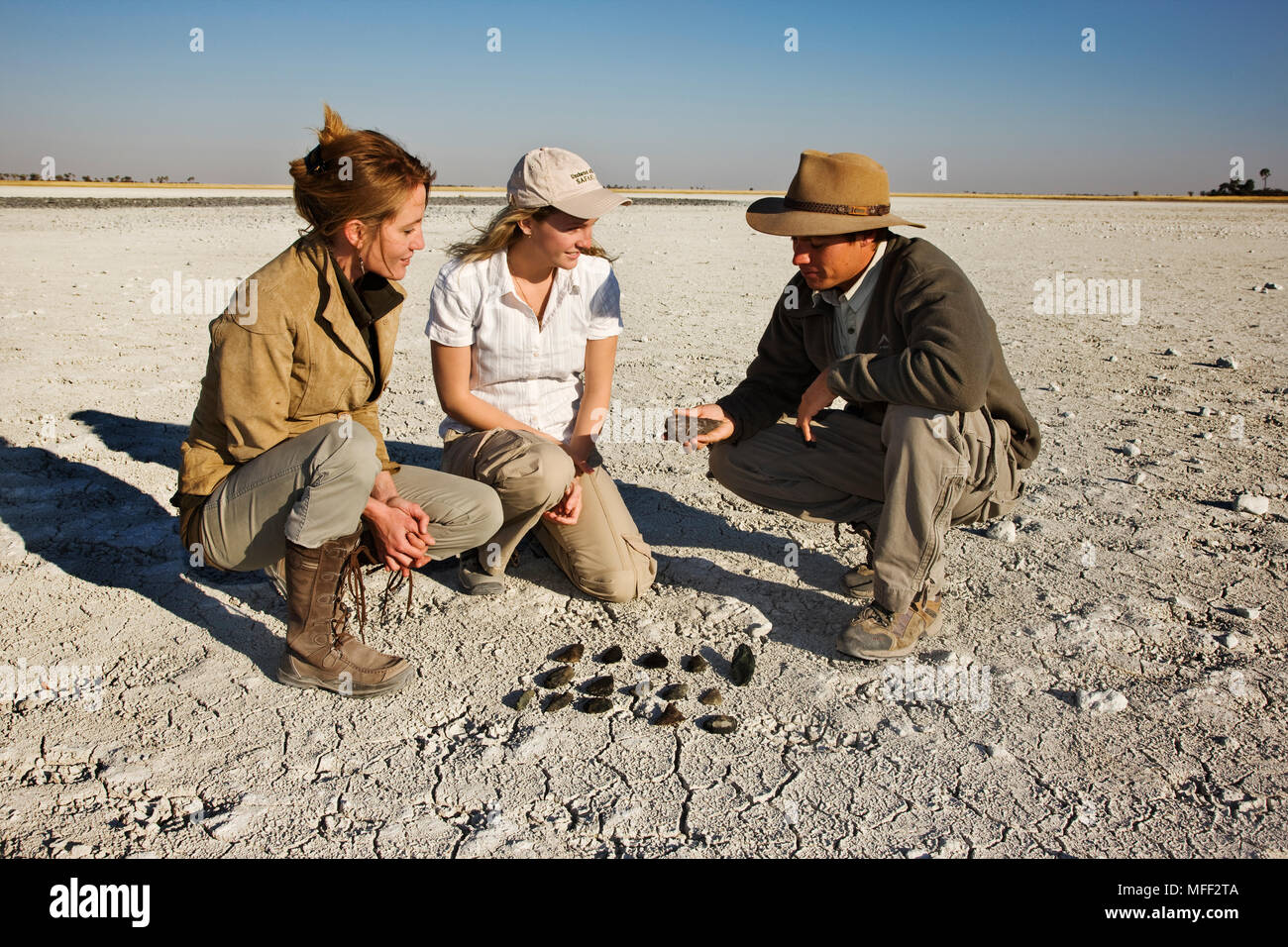 Guía que muestra a los turistas las herramientas de la edad de piedra colocadas sobre la superficie seca del Makgadikgadi Pans. Muchas de estas herramientas se encuentran en y alrededor de esto son Foto de stock