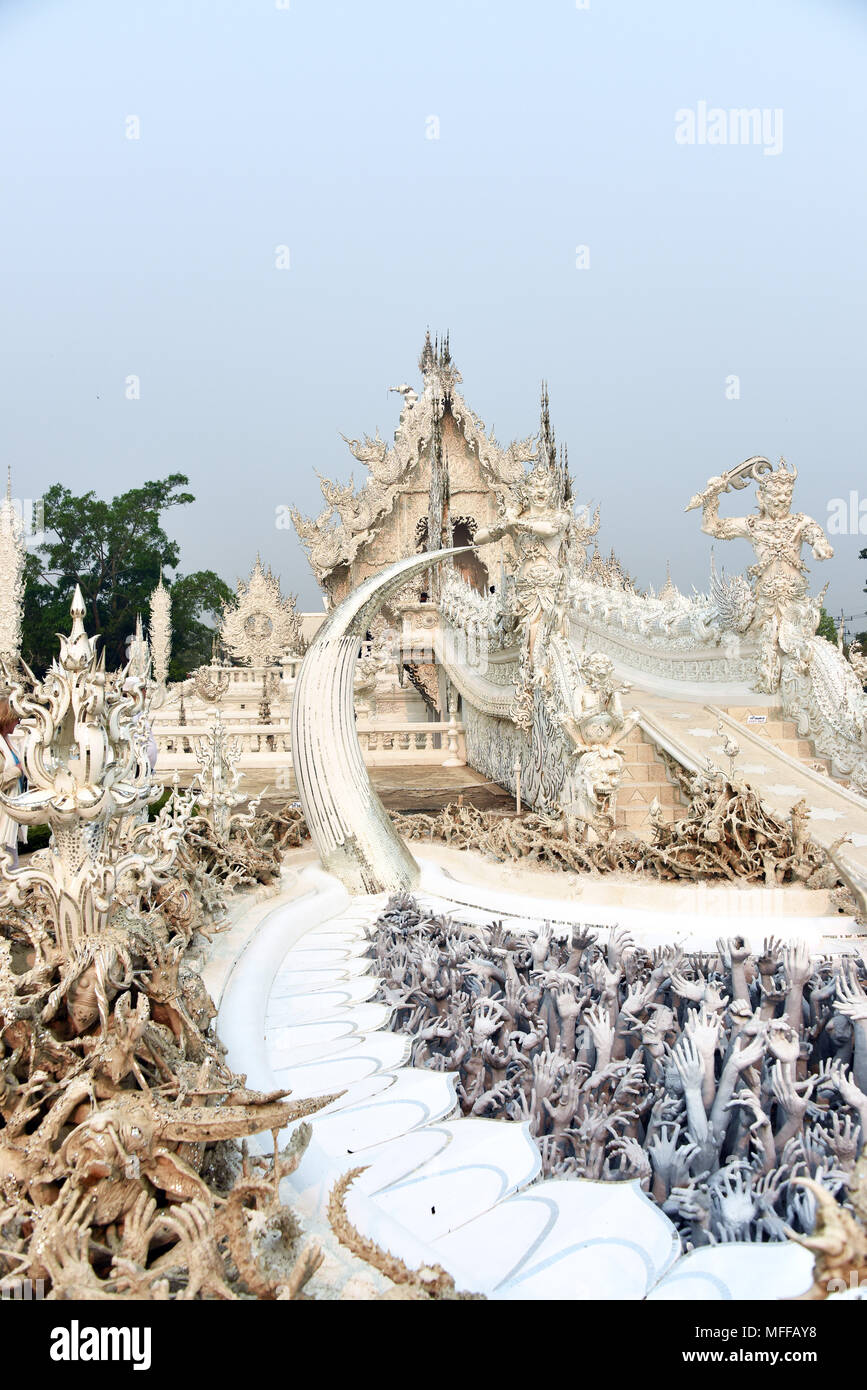 Manos de deseo desenfrenado y el puente del renacimiento conduce al edificio principal (Ubosot) de Wat Rong Khun o el Templo Blanco en Chiang Rai, al norte Foto de stock