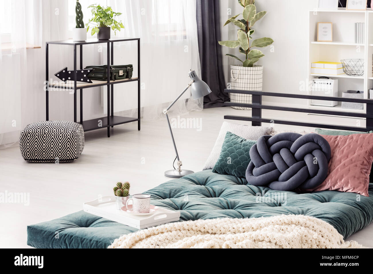 Nudo azul verde almohada sobre el futón en el luminoso interior del  dormitorio con telas pouf y lámpara Fotografía de stock - Alamy