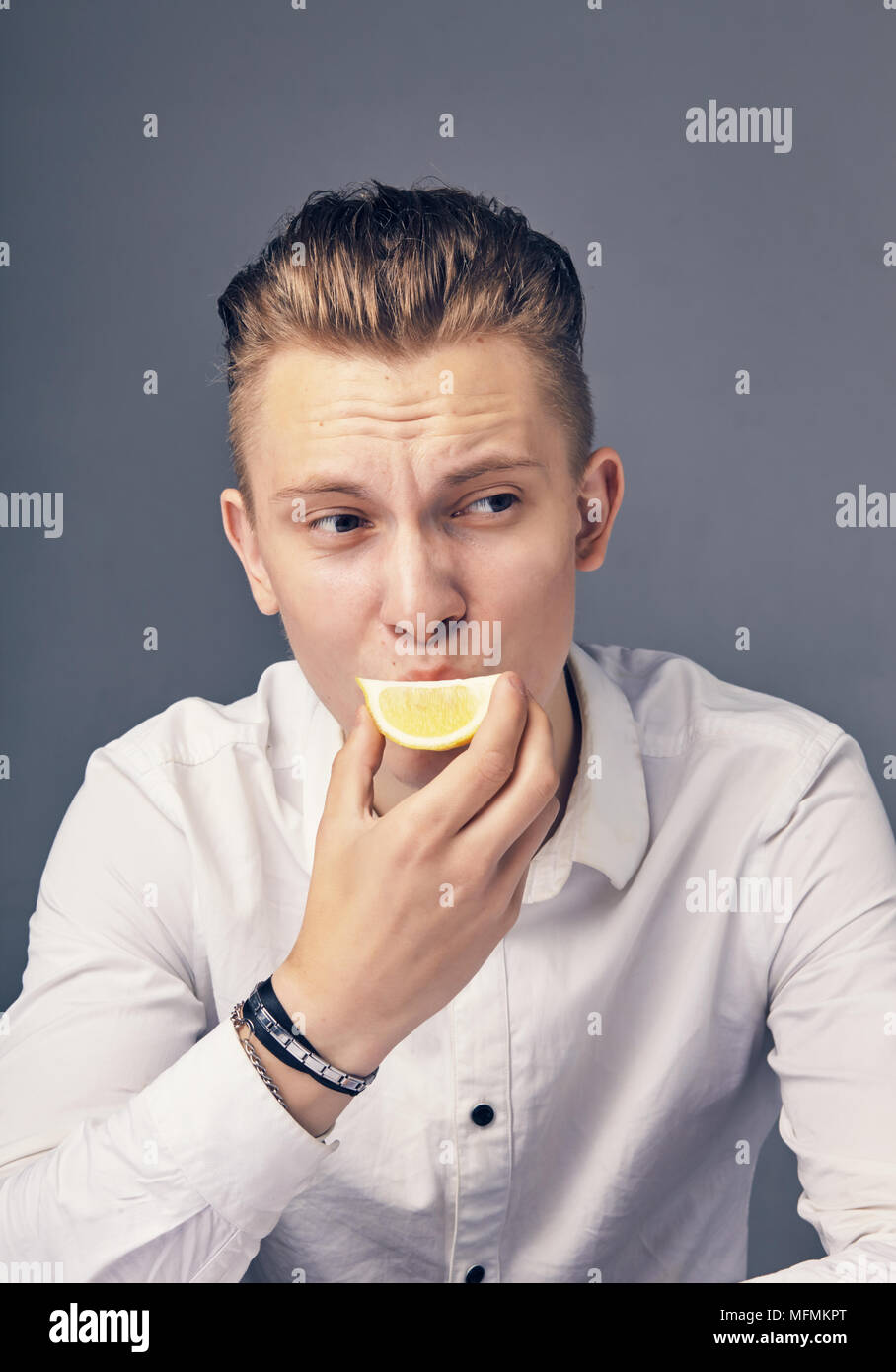 Joven tiene una emoción agria, mientras saborea un limón Foto de stock