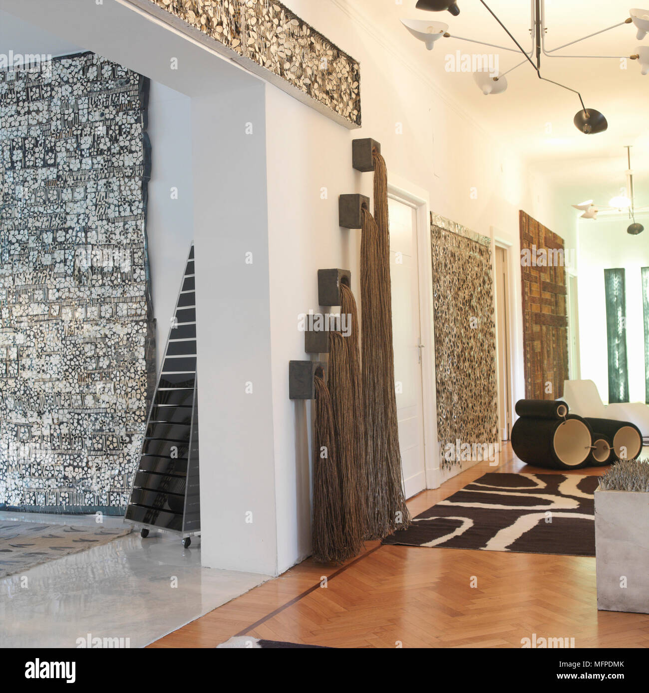 Un amplio vestíbulo moderno con pisos de madera, paredes altas, mat abstracto, arte abstracto y varias luces colgantes y apertura otra habitación Fotografía de stock Alamy