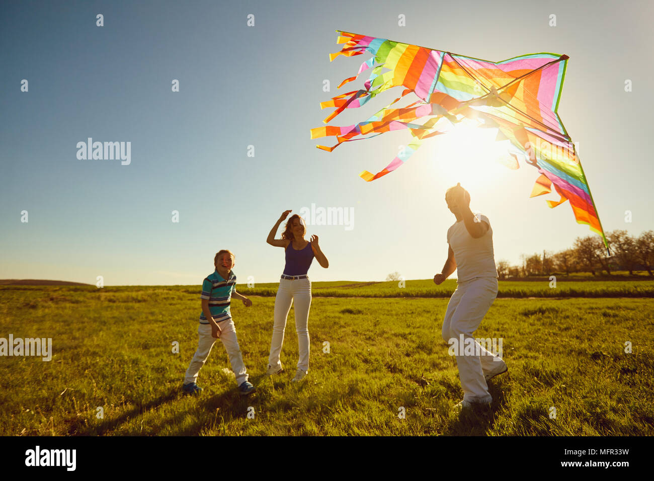 Familia feliz jugando con una cometa en la naturaleza en primavera, verano. Foto de stock