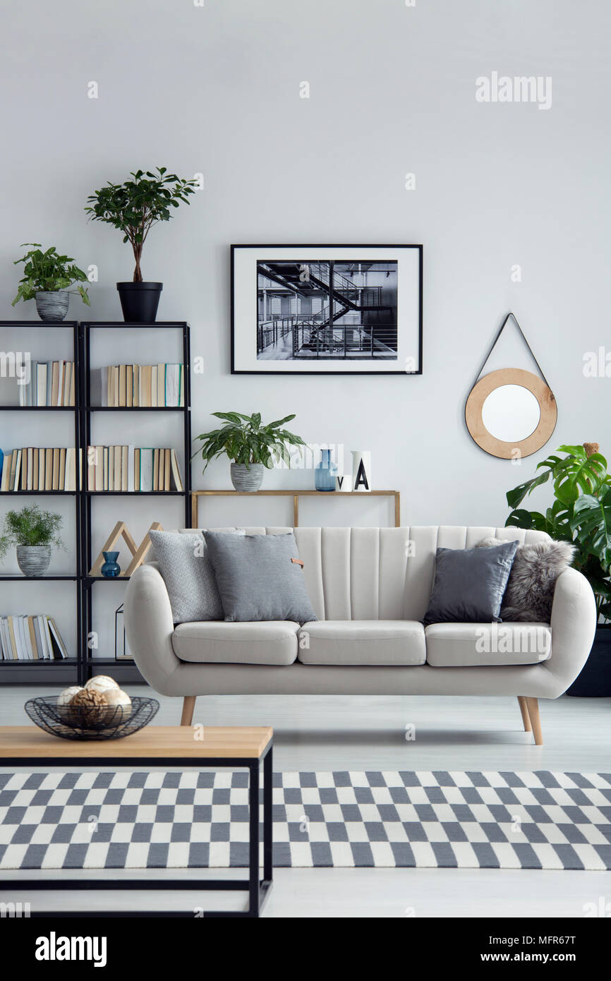 Sofá de color beige con un diseño sencillo y salón interior con muebles de  madera y negro, biblioteca en casa y plantas en macetas Fotografía de stock  - Alamy