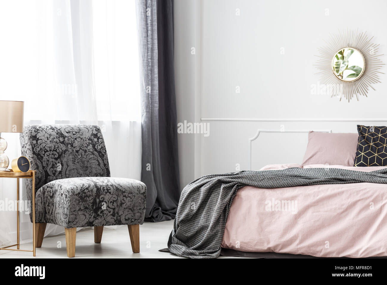 Hotel minimalista interior del dormitorio con sillón vintage de pie cerca  de la ventana y manta gris sobre la cama Fotografía de stock - Alamy