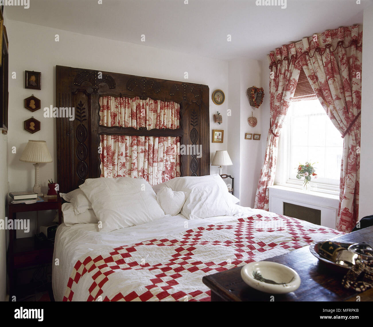 Estilo Dormitorio con cama de matrimonio con cabecero de madera y panel  rojo toile Juoy cortinas Fotografía de stock - Alamy