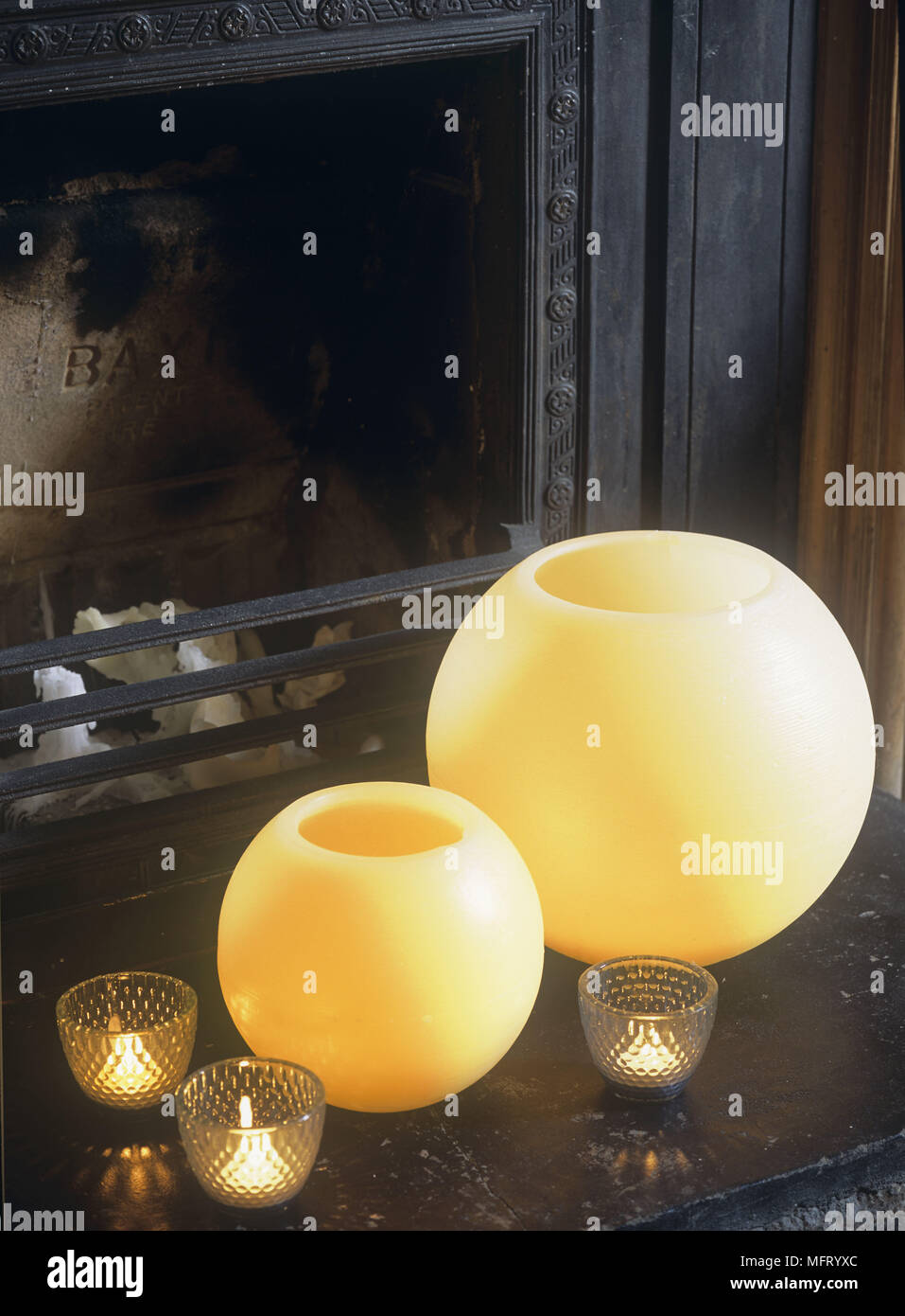 Amarillas grandes velas esféricas con velas en cristal decorativo en  chimenea Fotografía de stock - Alamy