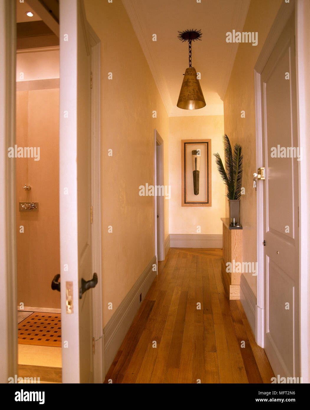 Un pasillo con paredes color crema, piso de madera, colgantes, lámparas  colgantes, y las puertas de las habitaciones contiguas Fotografía de stock  - Alamy