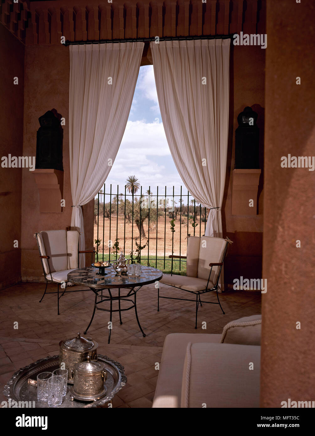 Salón marroquí detalle mesa redonda de metal sillas cortinas interiores  habitaciones influencia étnica colores cálidos Fotografía de stock - Alamy