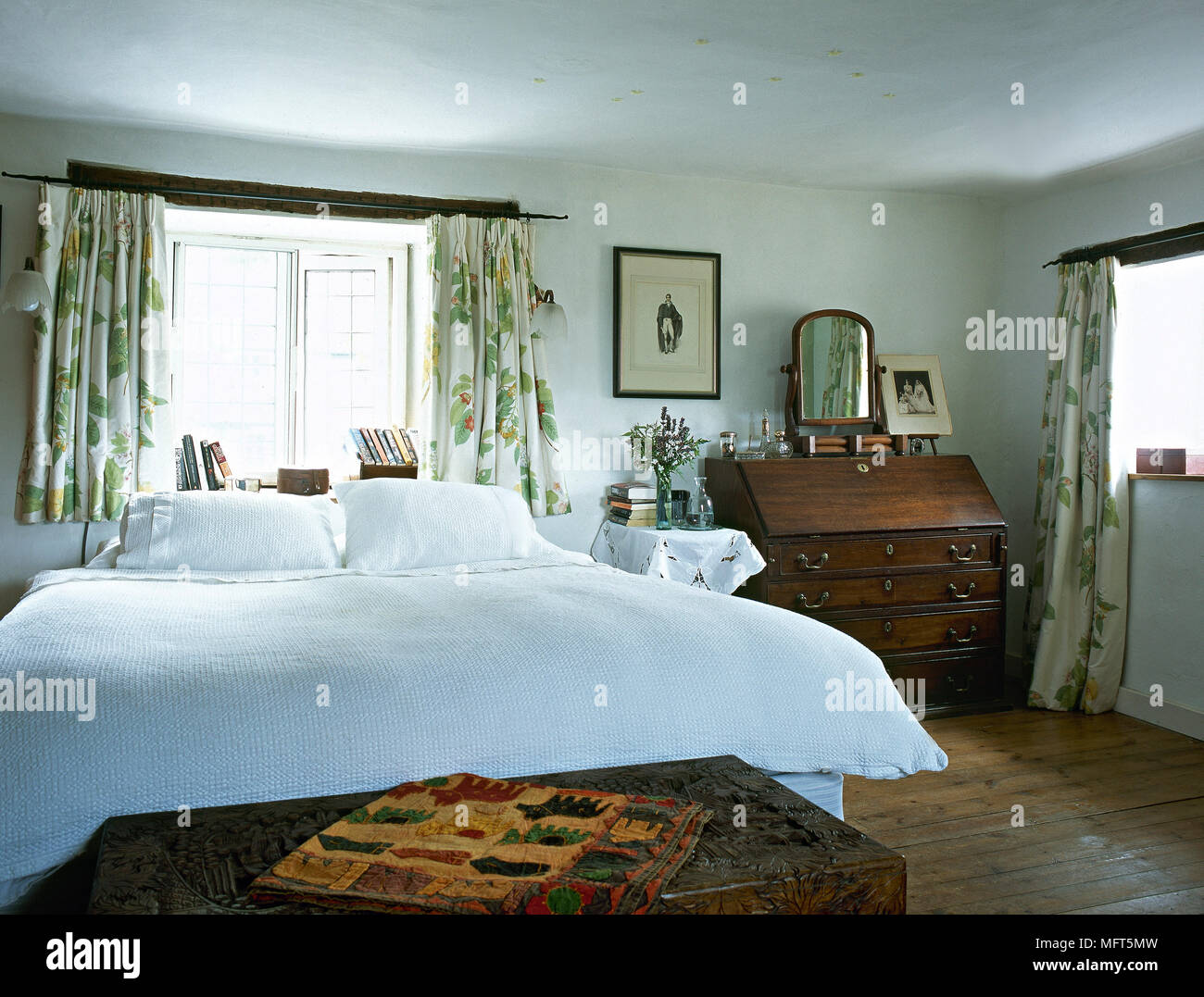 Cama doble en el dormitorio con dos ventanas y piso de madera Fotografía de  stock - Alamy