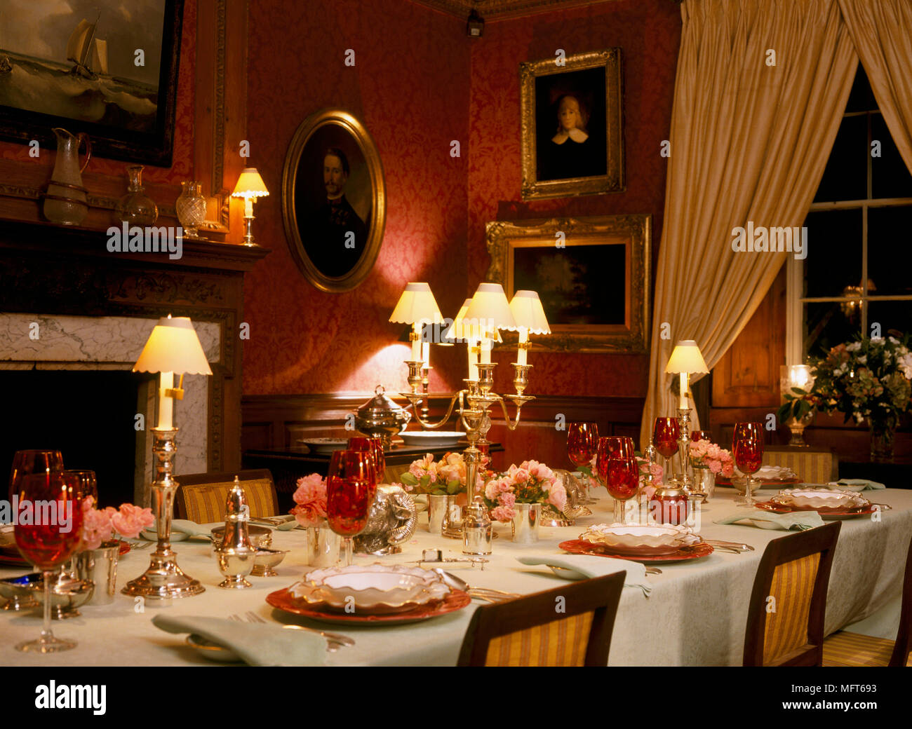 Un rojo tradicional, comedor con chimenea de mármol, mesa puesta con una  mesa oficial, luces encendidas en la noche, ambiente Fotografía de stock -  Alamy