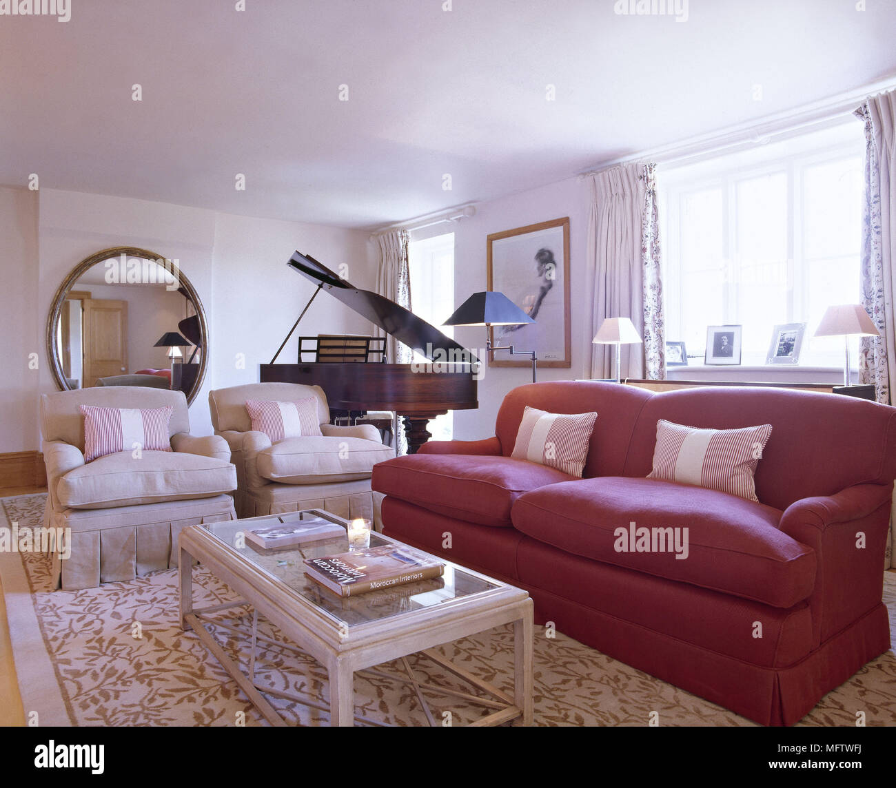 Una tradicional sala de con sofá rojo grand piano alfombra crema espejo sillones mesa de café Fotografía de -