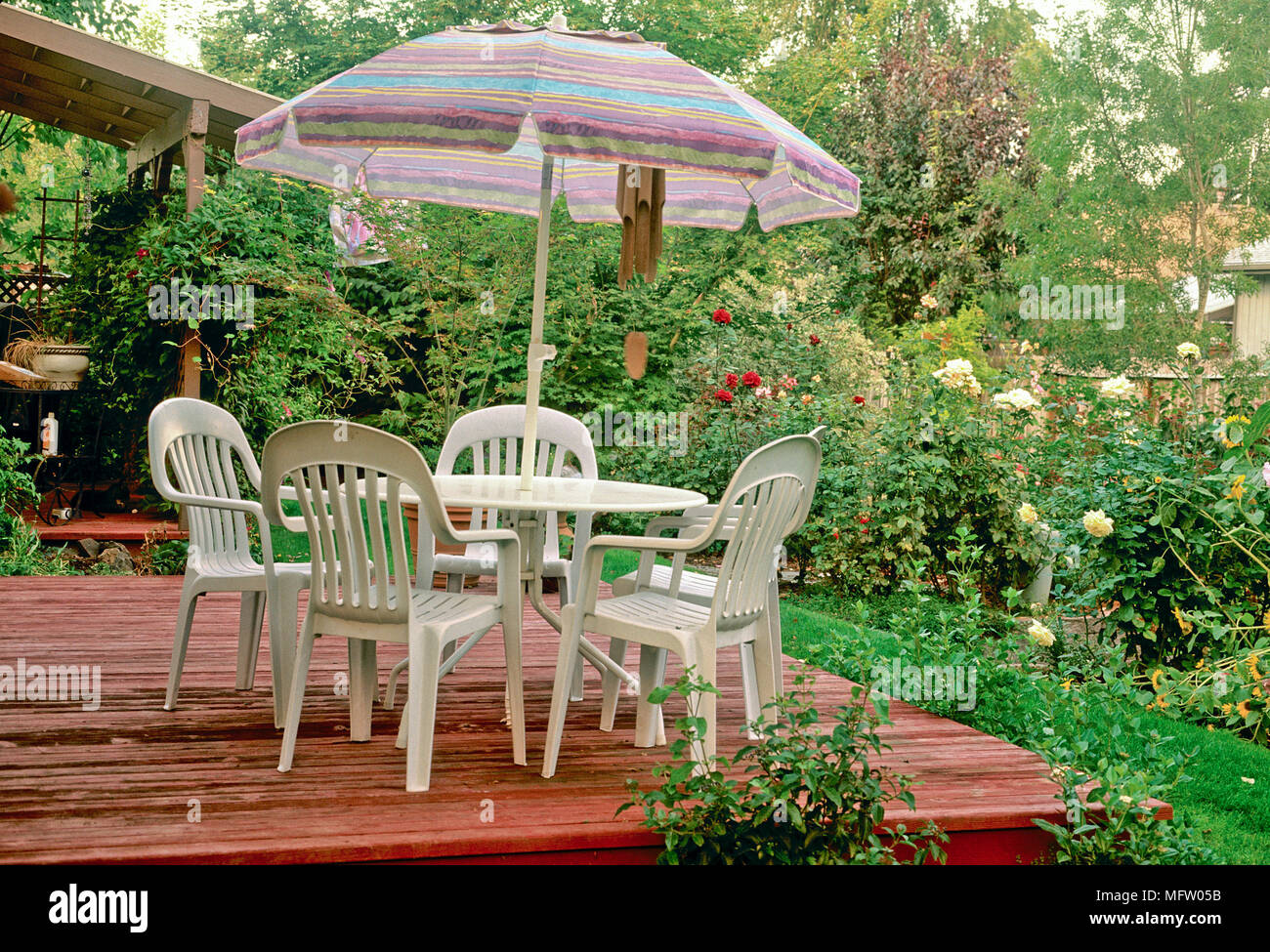 Mesas y sillas de plástico con sombrilla de patio decorado con vistas al  jardín Fotografía de stock - Alamy
