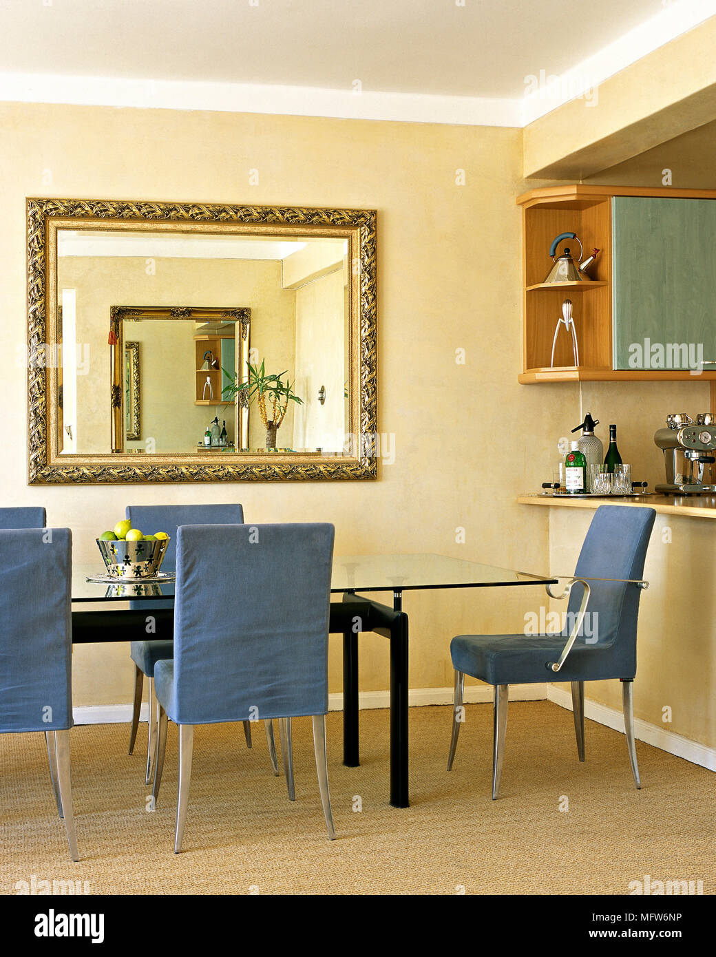 Un moderno, cocina abierta con comedor, mesa de cristal, sillas de cubierta  azul, espejo dorado Fotografía de stock - Alamy
