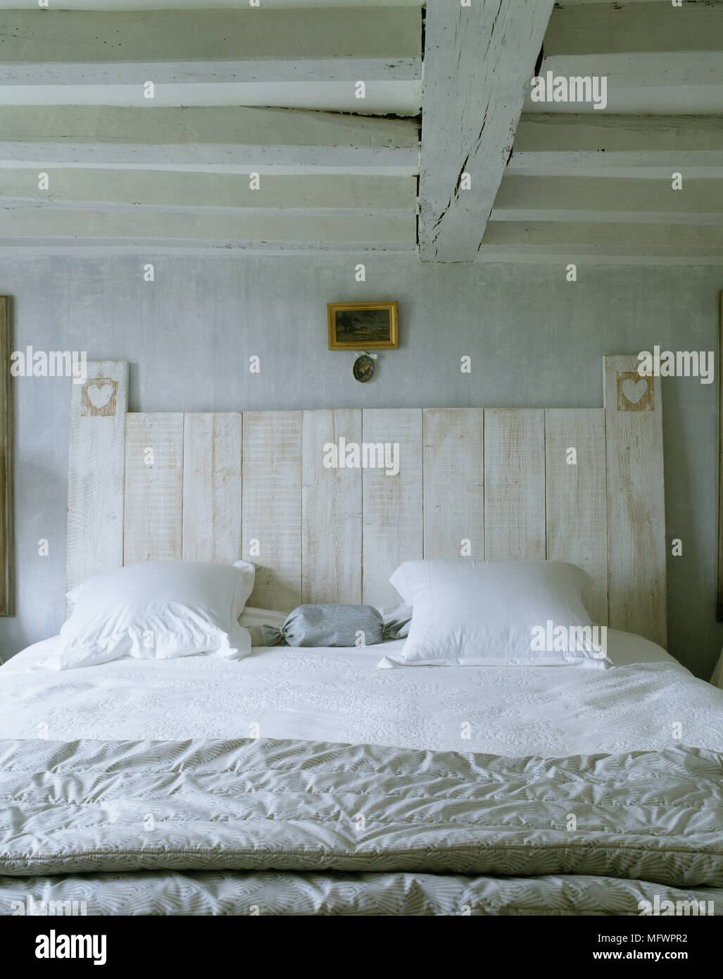 Dormitorio de estilo rústico con cama doble con ropa de cama blanca y  cabecera de madera Fotografía de stock - Alamy
